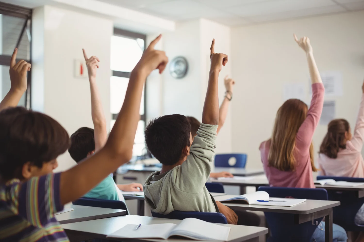 Niños levantando la mano en clase